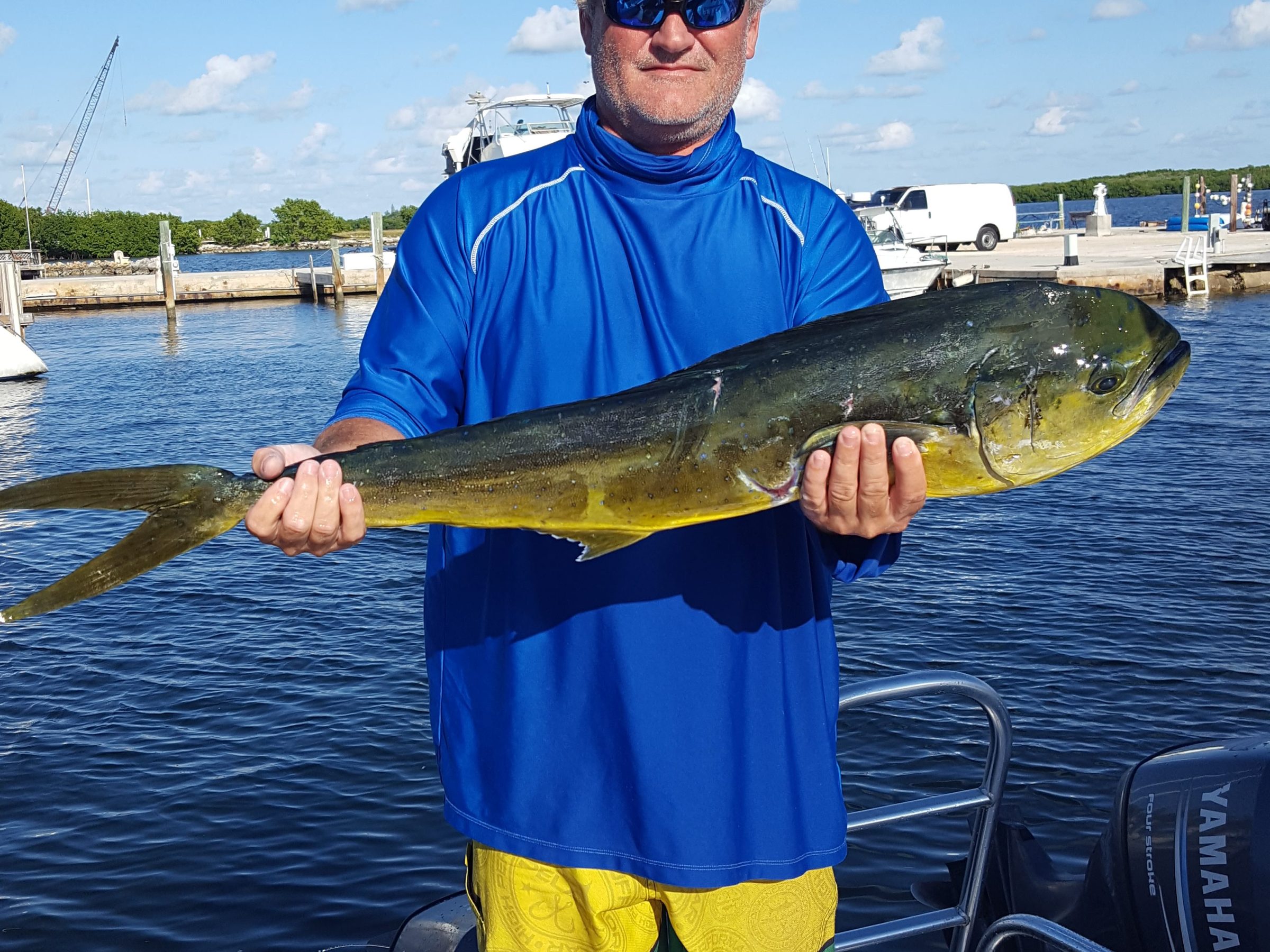 a man holding a fish on a boat in a body of water
