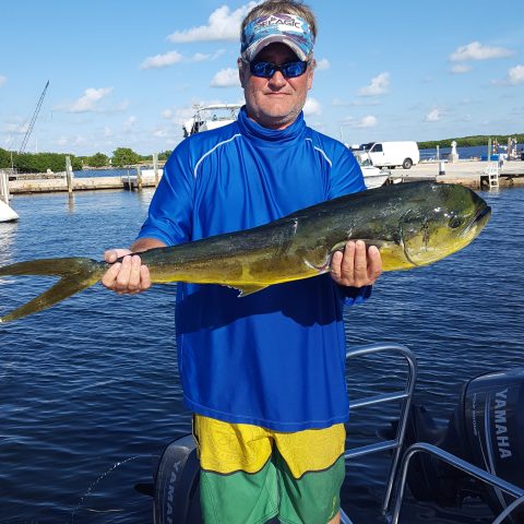 a man holding a fish on a boat in a body of water