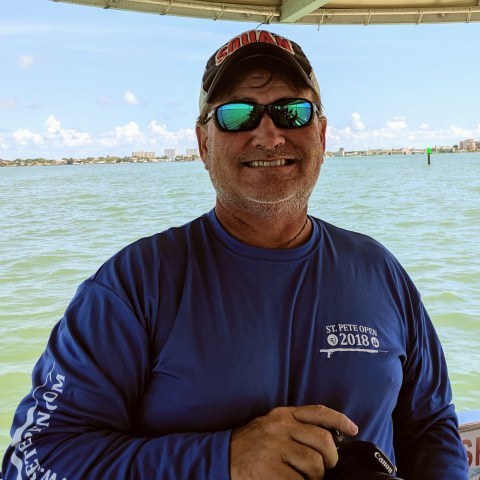 a man holding a fish on a boat in a body of water